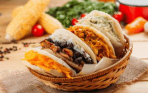 Um cesto com quatro arepas com diferentes sabores de recheio.