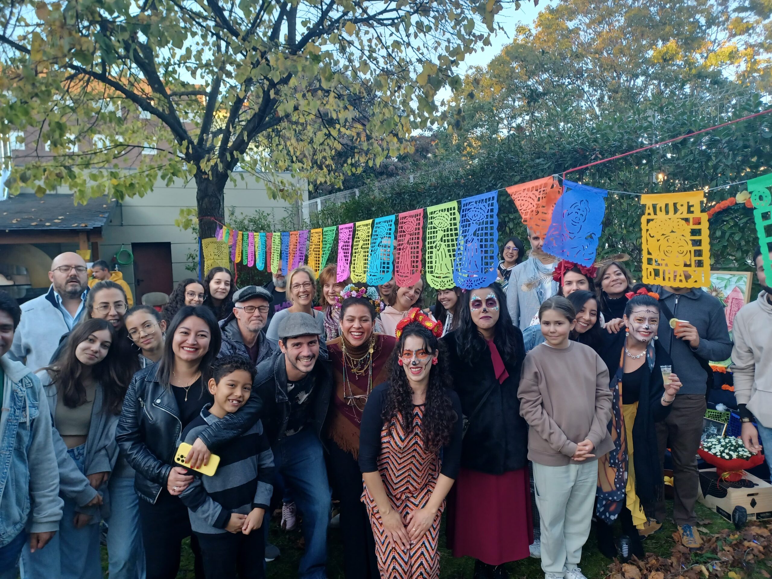 Grupo de pessoas reunidas em frente a bandeirinhas coloridas.